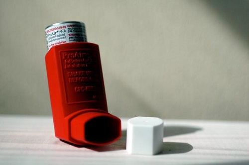 A red inhaler with its white cap
