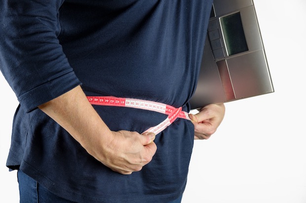 A person measuring their waist with a tape measure