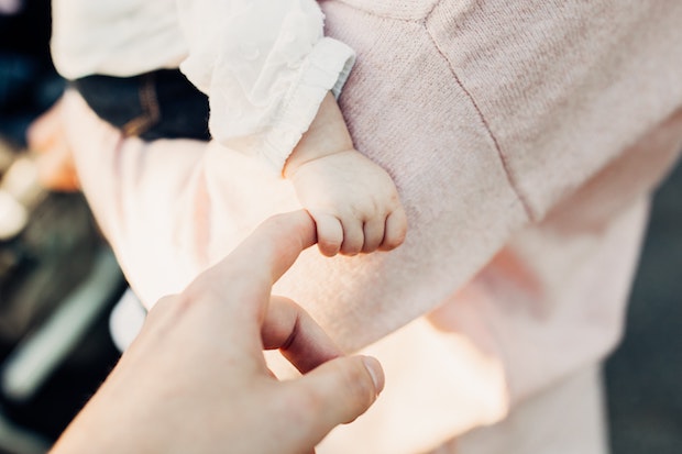 A hand holding a baby’s hand