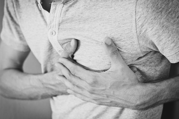 A black and white photo of a man clutching his heart