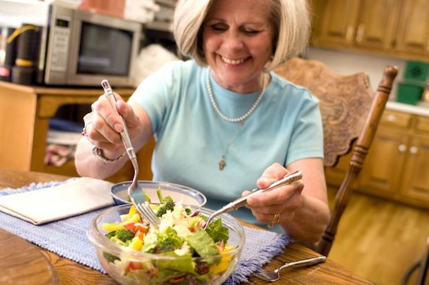 an older woman serving herself salad