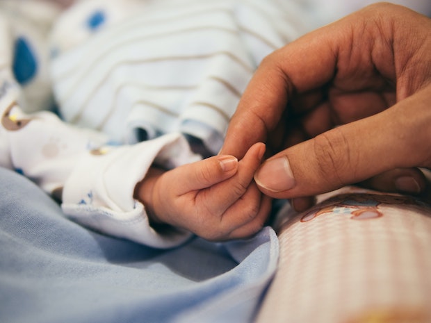 a person holding the hand of a newborn baby