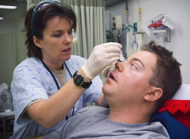 a health professional applying eye drops to a man